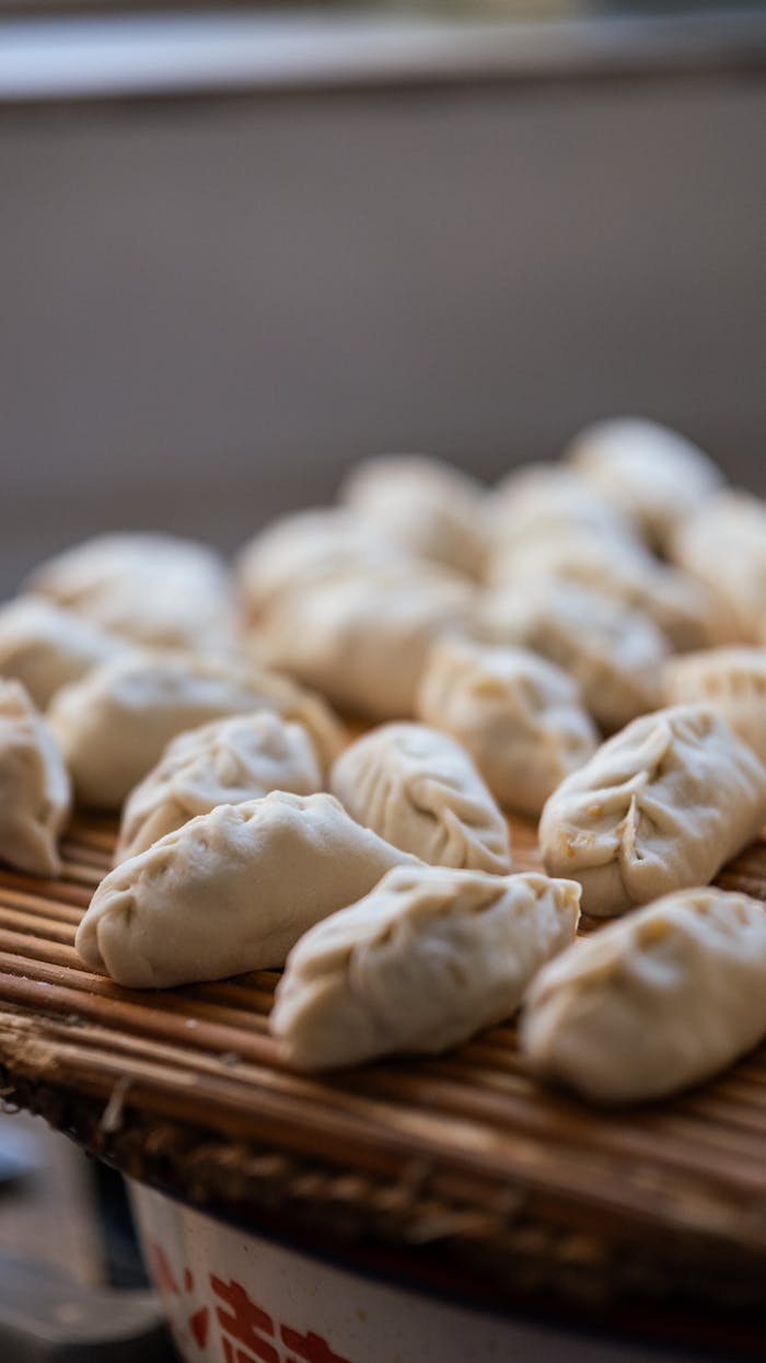 Fresh, homemade dumplings resting on a bamboo tray, ready for cooking.